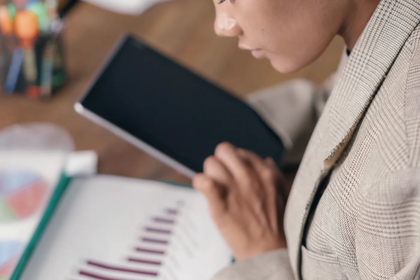 Une analyste lit un rapport ouvert sur un graphique en barres